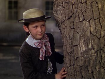 Movie still from “The Adventures of Tom Sawyer” (1938), directed by Norman Taurog – A boy in a hat leaning against a tree trunk; Medium shot, Low angle