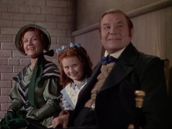 Movie still from “The Adventures of Tom Sawyer” (1938), directed by Norman Taurog – A man and a woman and a little girl sitting next to each other; Medium shot, High angle