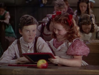 Movie still from “The Adventures of Tom Sawyer” (1938), directed by Norman Taurog – A boy and a little girl sitting in front of an ipad; Medium shot, High angle
