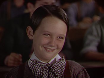 Movie still from “The Adventures of Tom Sawyer” (1938), directed by Norman Taurog – A young boy wearing a bow tie smiling for the camera; Close Up shot, High angle
