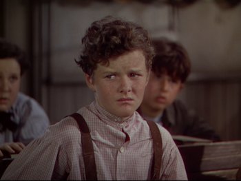 Movie still from “The Adventures of Tom Sawyer” (1938), directed by Norman Taurog – A young boy wearing suspenders and a checkered shirt; Close Up shot, Over the shoulder angle