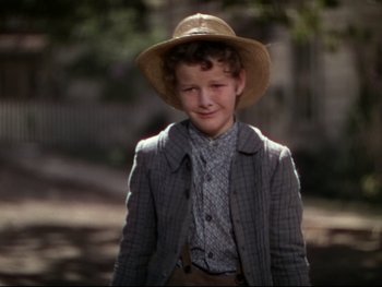 Movie still from “The Adventures of Tom Sawyer” (1938), directed by Norman Taurog – A young boy wearing a straw hat and a jacket; Medium shot, Low angle