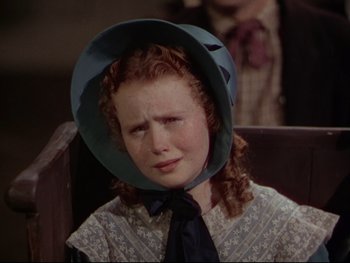 Movie still from “The Adventures of Tom Sawyer” (1938), directed by Norman Taurog – A young girl wearing a blue hat with a sad look on her face; Close Up shot, High angle