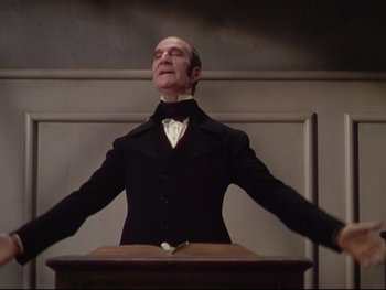 Movie still from “The Adventures of Tom Sawyer” (1938), directed by Norman Taurog – An old man in a suit and bow tie standing in front of a podium; Medium shot, Low angle