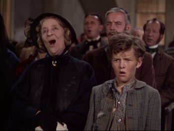 Movie still from “The Adventures of Tom Sawyer” (1938), directed by Norman Taurog – An older woman and a young boy sing in a choir; Medium shot, Low angle