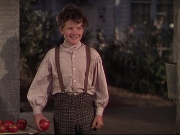 Movie still from “The Adventures of Tom Sawyer” (1938), directed by Norman Taurog – A young boy holding two red apples in his hands; Medium shot, Low angle