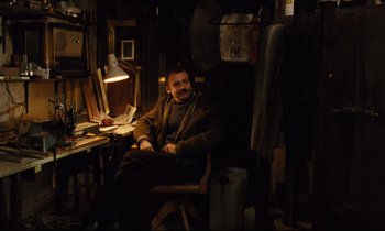 Movie still from “The American Friend” (1977), directed by Wim Wenders – A man sitting in a chair in a room; Medium shot, High angle