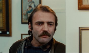 Movie still from “The American Friend” (1977), directed by Wim Wenders – A person with a mustache; Close Up shot, Low angle