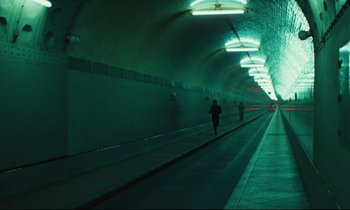 Movie still from “The American Friend” (1977), directed by Wim Wenders – People are walking down a tunnel in the dark; Extreme Wide shot, High angle
