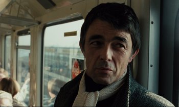 Movie still from “The American Friend” (1977), directed by Wim Wenders – A man in a suit sitting on a train; Close Up shot, Over the shoulder angle