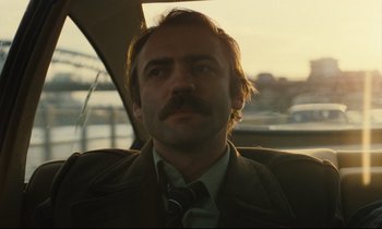 Movie still from “The American Friend” (1977), directed by Wim Wenders – A person wearing a suit and tie; Close Up shot, Low angle