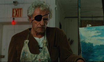 Movie still from “The American Friend” (1977), directed by Wim Wenders – An older man wearing an eye patch and an apron; Close Up shot, Low angle