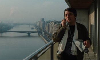 Movie still from “The American Friend” (1977), directed by Wim Wenders – A man talking on a phone while standing on a balcony; Medium shot, Low angle