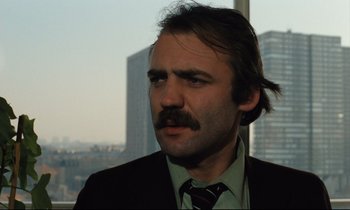 Movie still from “The American Friend” (1977), directed by Wim Wenders – A person wearing a suit and tie; Close Up shot, Low angle