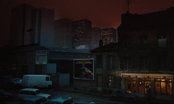 Movie still from “The American Friend” (1977), directed by Wim Wenders – A street scene with a van parked on the side of the road; Extreme Wide shot, High angle