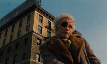 Movie still from “The American Friend” (1977), directed by Wim Wenders – An old man wearing a pirate eye patch; Medium shot, Low angle