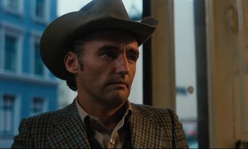 Movie still from “The American Friend” (1977), directed by Wim Wenders – A man wearing a cowboy hat and a jacket; Close Up shot, Over the shoulder angle