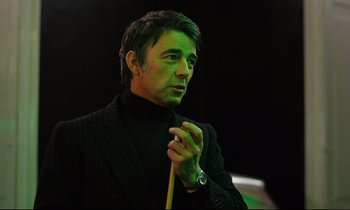 Movie still from “The American Friend” (1977), directed by Wim Wenders – A man in a black suit holding a pool cue; Close Up shot, Low angle