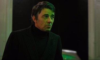 Movie still from “The American Friend” (1977), directed by Wim Wenders – A man in a black jacket is looking to his left; Close Up shot, Low angle