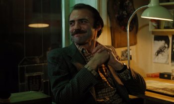 Movie still from “The American Friend” (1977), directed by Wim Wenders – A man in a suit and tie putting on a tie; Close Up shot, Low angle