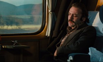 Movie still from “The American Friend” (1977), directed by Wim Wenders – A man sitting on a train looking out the window; Medium shot, Low angle