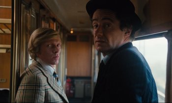 Movie still from “The American Friend” (1977), directed by Wim Wenders – A man and a woman standing next to each other in a train; Medium shot, Low angle