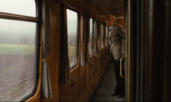 Movie still from “The American Friend” (1977), directed by Wim Wenders – A man standing on a train looking out of a window; Wide shot, Over the shoulder angle