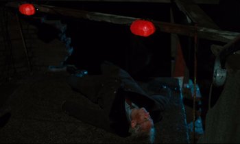 Movie still from “The American Friend” (1977), directed by Wim Wenders – A man laying on the ground in the dark; Wide shot, Overhead angle