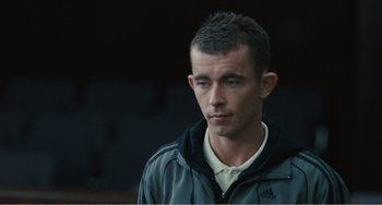 Movie still from “The Angels' Share” (2012), directed by Ken Loach – A young man in a gray jacket looks to his left; Close Up shot, High angle