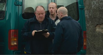 Movie still from “The Angels' Share” (2012), directed by Ken Loach – A group of men standing next to each other on a train; Medium shot, Over the shoulder angle