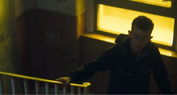 Movie still from “The Angels' Share” (2012), directed by Ken Loach – A man leaning against a railing in a room; Medium shot, Low angle