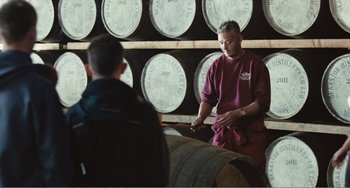 Movie still from “The Angels' Share” (2012), directed by Ken Loach – A man standing in front of a barrel in a room; Medium shot, Over the shoulder angle