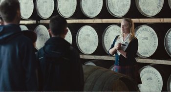 Movie still from “The Angels' Share” (2012), directed by Ken Loach – A woman standing in front of a wall of whiskey barrels; Medium shot, Over the shoulder angle