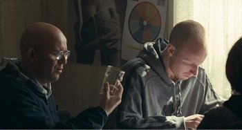Movie still from “The Angels' Share” (2012), directed by Ken Loach – A man sitting in front of another man holding something; Medium shot, Over the shoulder angle