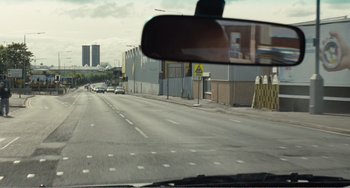 Movie still from “The Angels' Share” (2012), directed by Ken Loach – A rear view mirror on the side of a car; Extreme Wide shot, Over the shoulder angle