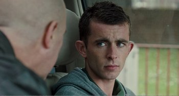 Movie still from “The Angels' Share” (2012), directed by Ken Loach – A young man sitting in the back seat of a car; Close Up shot, Over the shoulder angle