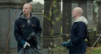 Movie still from “The Angels' Share” (2012), directed by Ken Loach – Two men are standing in front of a grave; Medium shot, Over the shoulder angle