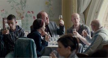 Movie still from “The Angels' Share” (2012), directed by Ken Loach – A group of people sitting at a table drinking wine; Medium shot, Over the shoulder angle