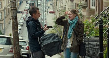 Movie still from “The Angels' Share” (2012), directed by Ken Loach – A man and a woman standing next to each other on the street; Medium shot, Over the shoulder angle
