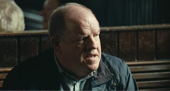 Movie still from “The Angels' Share” (2012), directed by Ken Loach – An older man with a beard is looking into the distance; Close Up shot, Over the shoulder angle