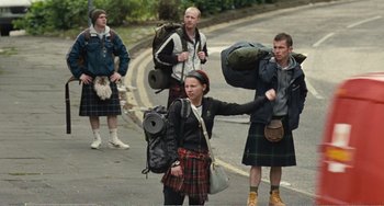 Movie still from “The Angels' Share” (2012), directed by Ken Loach – A group of people walking down a street with backpacks; Wide shot, High angle