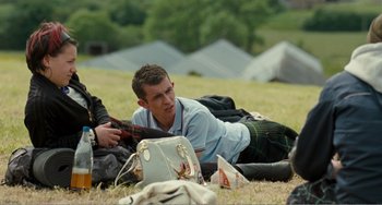 Movie still from “The Angels' Share” (2012), directed by Ken Loach – A man sitting on the ground in the grass; Medium shot, Over the shoulder angle