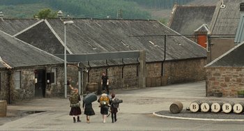 Movie still from “The Angels' Share” (2012), directed by Ken Loach – A group of people walking down a street with umbrellas; Extreme Wide shot, High angle