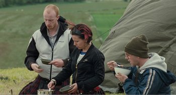 Movie still from “The Angels' Share” (2012), directed by Ken Loach – A group of people standing next to each other near a tent; Medium shot, Over the shoulder angle