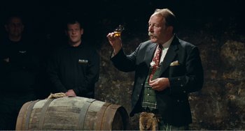 Movie still from “The Angels' Share” (2012), directed by Ken Loach – A man holding a glass of wine in front of another man; Medium shot, Over the shoulder angle