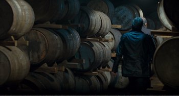 Movie still from “The Angels' Share” (2012), directed by Ken Loach – A man standing in front of a bunch of wooden barrels; Medium shot, High angle