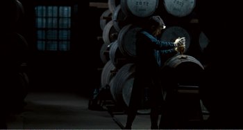 Movie still from “The Angels' Share” (2012), directed by Ken Loach – A man standing next to a stack of barrels; Medium shot, Low angle