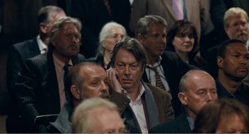 Movie still from “The Angels' Share” (2012), directed by Ken Loach – A group of people sitting in a room; Close Up shot, Over the shoulder angle