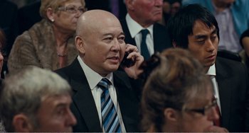 Movie still from “The Angels' Share” (2012), directed by Ken Loach – A man in a suit talking on a cell phone; Close Up shot, Over the shoulder angle