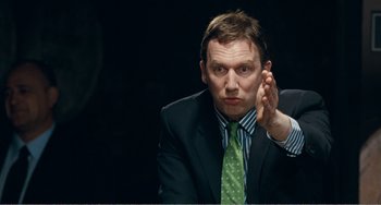 Movie still from “The Angels' Share” (2012), directed by Ken Loach – A man in a suit and tie sitting in front of a camera; Close Up shot, Over the shoulder angle